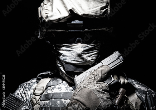 Fototapeta Special operations forces soldier in combat helmet with hidden behind balaclava and dark glasses face posing with sidearm service pistol in hand