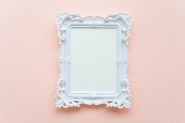 White vintage photo frame on pink pastel wooden background flat lay top view style