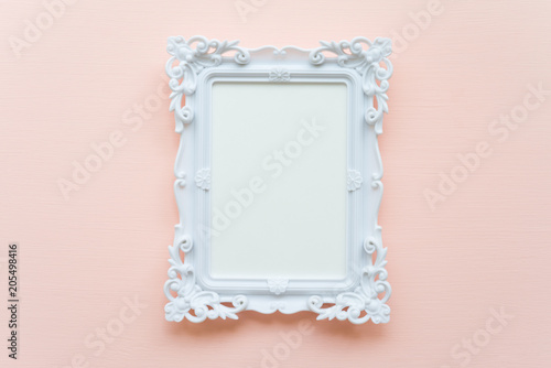 White vintage photo frame on pink pastel wooden background flat lay top view style