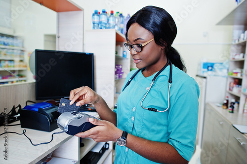 African american pharmacist working in drugstore at hospital pharmacy. African healthcare. Work with payment terminal and credit card.