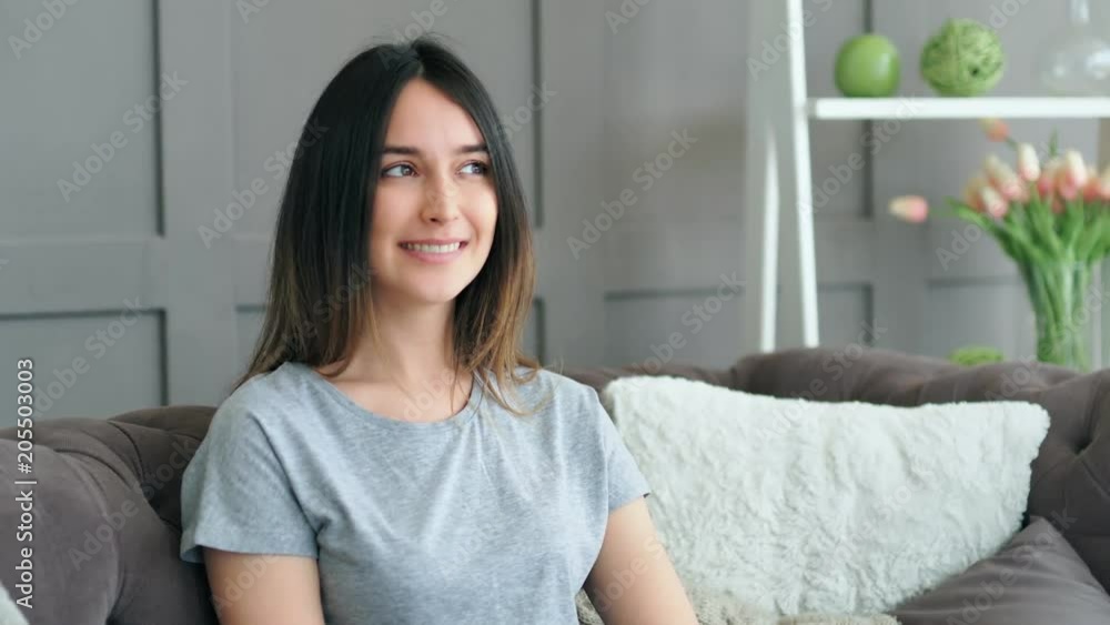 Beautiful young woman resting on sofa at home. Portrait of smiling girl looking at camera Beautiful young woman resting on sofa at home. Portrait of smiling girl looking at camera
