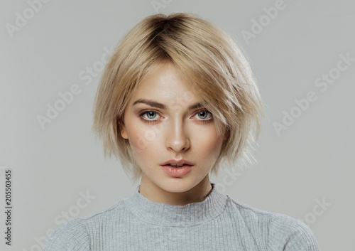 Beauty portrait of female face with natural skin looking at camera isolated on grey