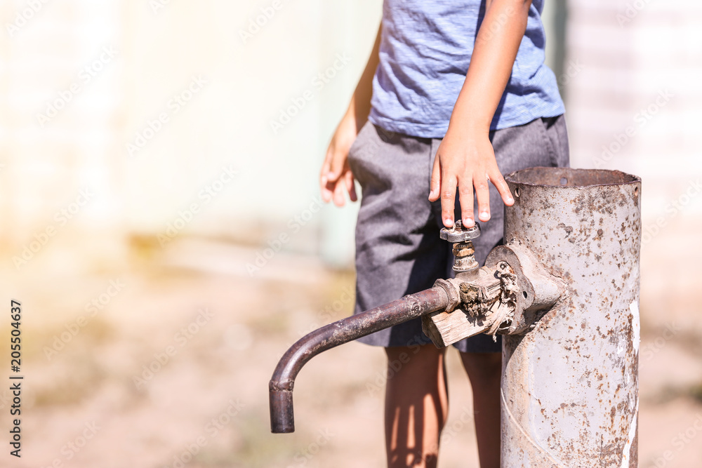 African American child near water tap outdoors. Water scarcity concept