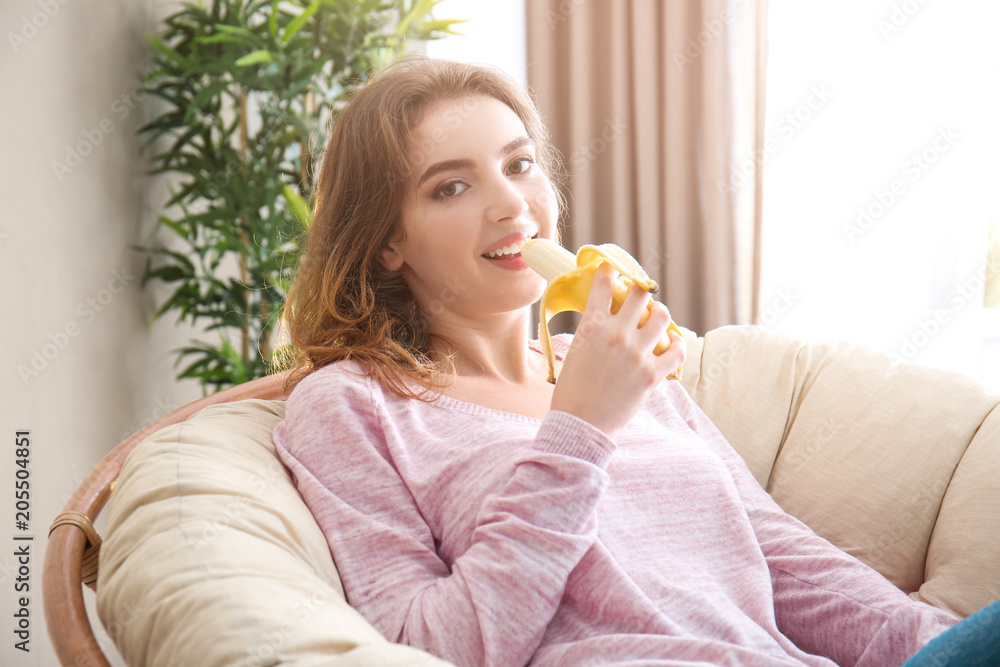 Young woman eating banana at home Young woman eating banana at home