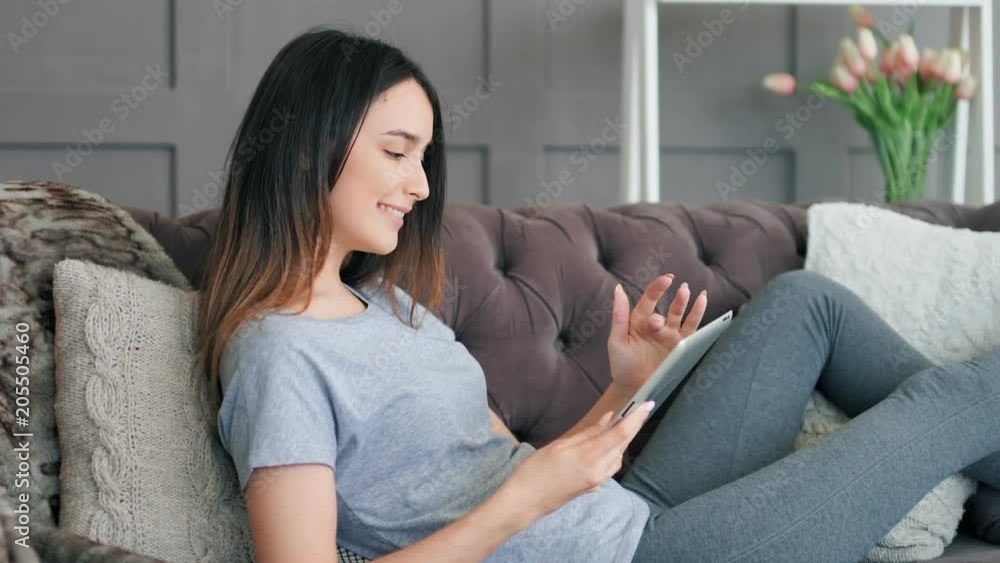 Young pretty woman sitting on sofa with tablet pc Young pretty woman sitting on sofa with tablet pc