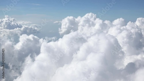 Beautiful cloudy sky. Fluffy сumulus clouds illuminated by sunlight passing by camera. Gorgeous skyscape or cloudscape. Concept of heaven and tranquility. Aerial view from window of flying airplane.