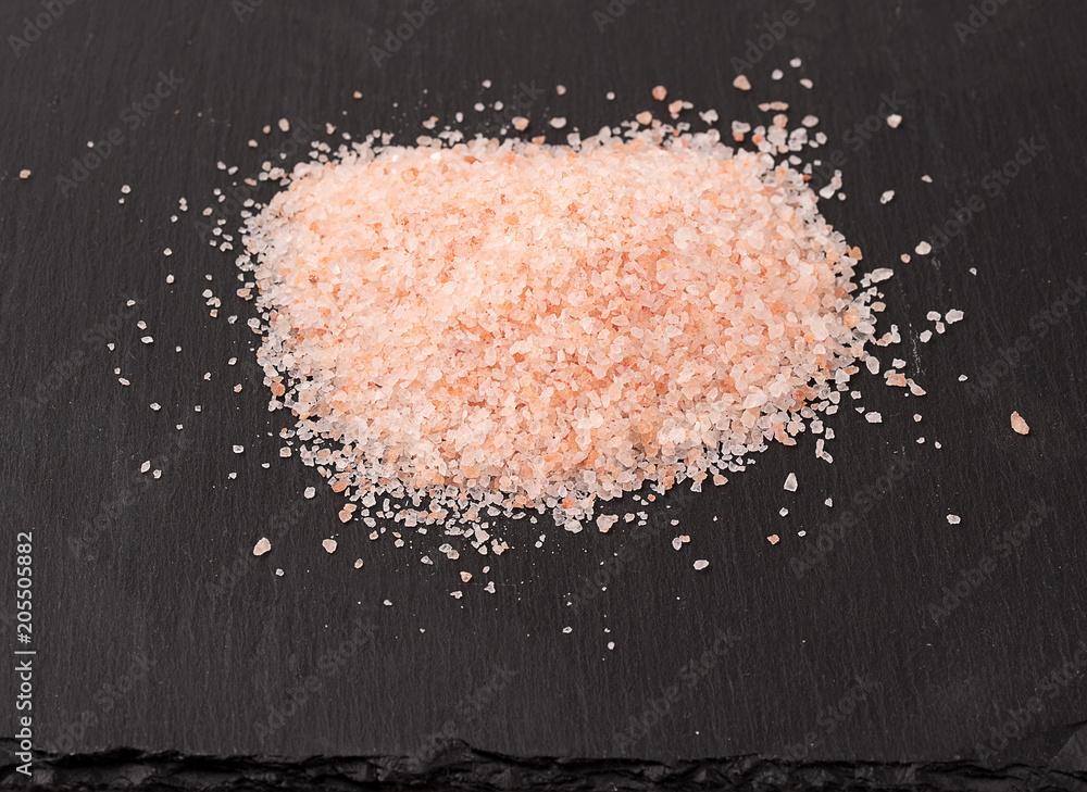 Himalayan pink salt on black stone background Himalayan pink salt on black stone background