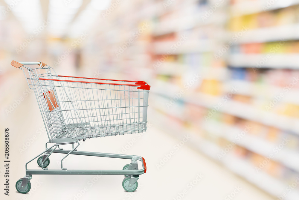 Empty red shopping cart with abstract blur supermarket discount store aisle and product shelves interior defocused background Empty red shopping cart with abstract blur supermarket discount store aisle and product shelves interior defocused background