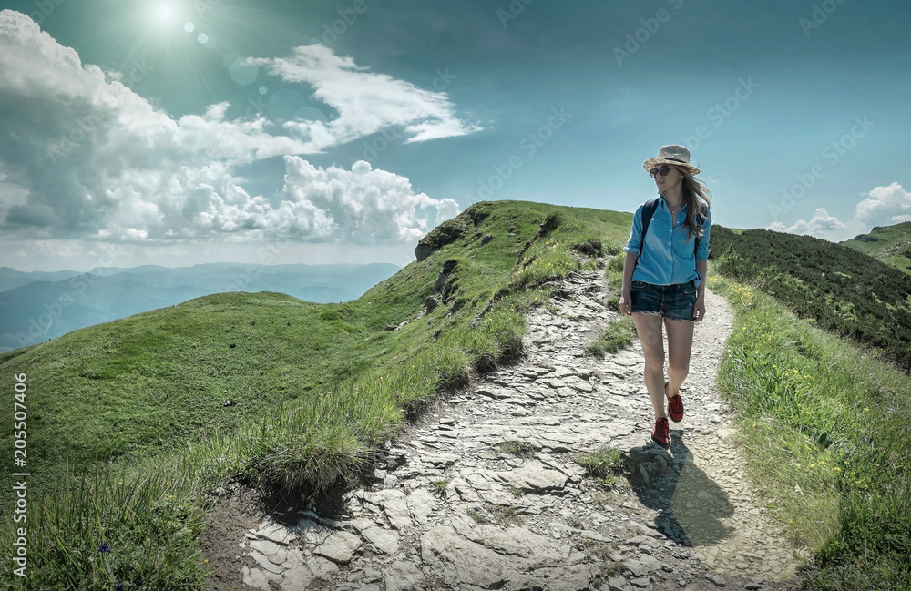Fototapeta premium Woman hiking in mountains at sunny day time.