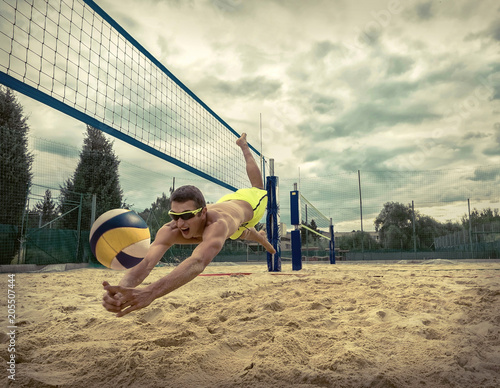 Beach Volleyball player in sunglasses flying for ball under sunl
