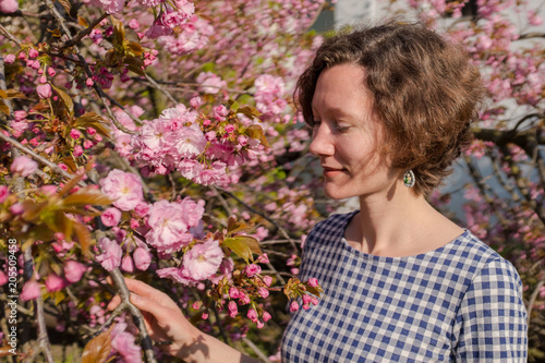 Outdoor portrait of a beautiful woman near sakura tree with flowers. 
