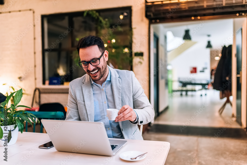 Man laughing while looking at laptop screen while having a cup of coffee. Man laughing while looking at laptop screen while having a cup of coffee.
