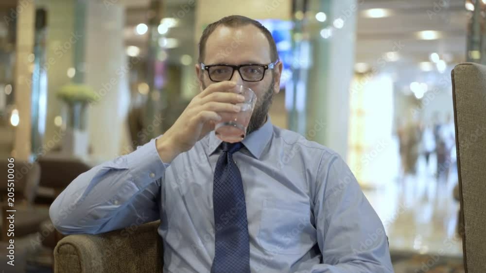 Happy businessman drinking alcoholic drink in pub and talking to the camera
Happy businessman drinking alcoholic drink in pub and talking to the camera
