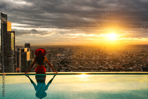 Photography woman enjoy city light in background in swimming pool on rooftop of building