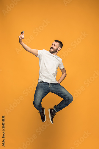 Time to take selfie. Full length of handsome young man taking selfie while jumping