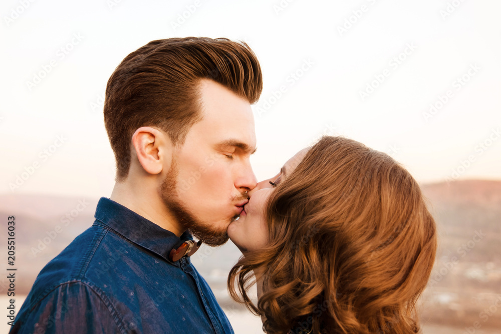 Couple in love kisses on the background of hills and river. Side view. Couple in love kisses on the background of hills and river. Side view.