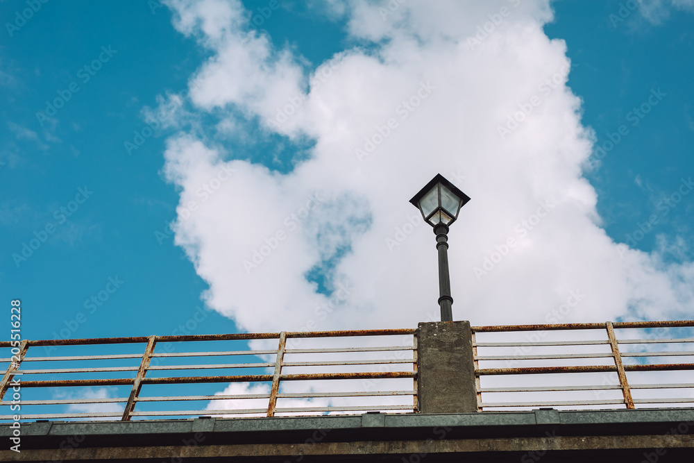 Flashlight on the bridge next to a small town. In the back there is a beautiful blue sky Flashlight on the bridge next to a small town. In the back there is a beautiful blue sky
