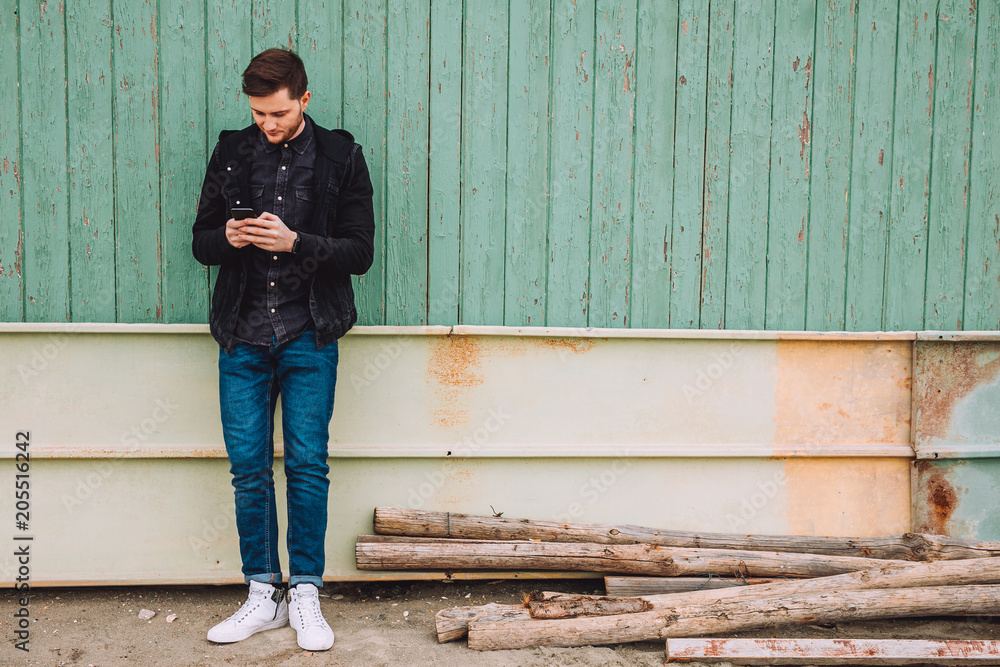 Young man with beard write message to his girlfriend .in the back are wooden planks of green color .the boy is positive Young man with beard write message to his girlfriend .in the back are wooden planks of green color .the boy is positive
