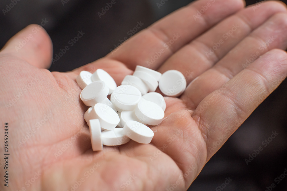 White pills in hand on black background closeup White pills in hand on black background closeup