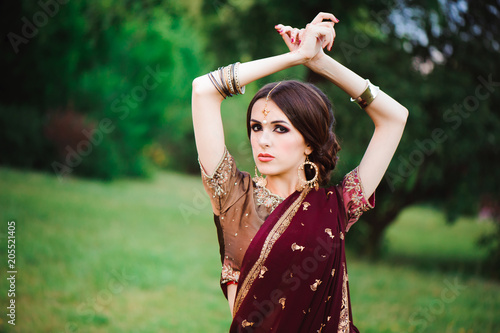 Indian girl with oriental jewellery and make-up henna applied to hand. Brunette Hindu model girl with Indian jewels.