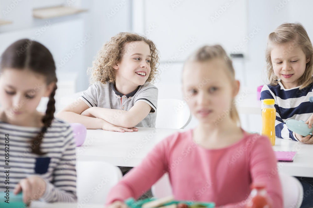 Happy boy sitting at dining table with girl in the school's canteen Happy boy sitting at dining table with girl in the school's canteen