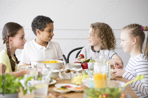 Smiling multicultural group of children eating food during birthday party
