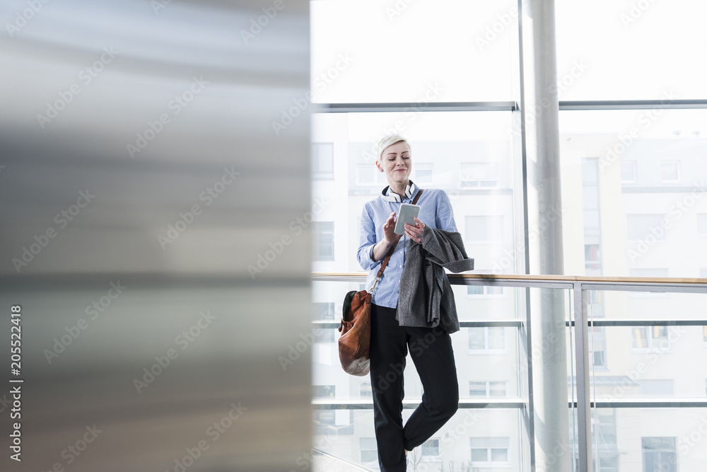 Smiling woman in office building using cell phone Smiling woman in office building using cell phone