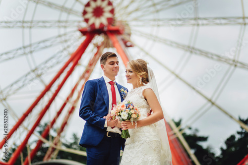 romantic wedding couple of newlyweds on the background of ferris wheel.