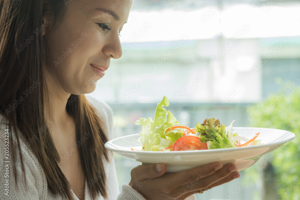 Cafe woman eating salads in coffee shop sitting next to the window smiling. Cafe woman eating salads in coffee shop sitting next to the window smiling.