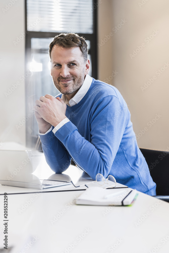 Portrait of smiling businessman with laptop in office Portrait of smiling businessman with laptop in office