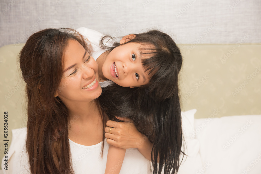 Mother and daughter enjoy in bed at home