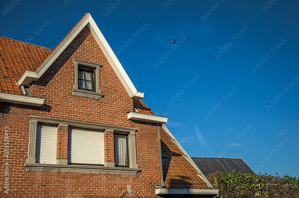Detail of brick building facade and roofs at sunset in the City Center of Tielt. Charming and quiet village in the countryside, near Ghent and surrounded by agricultural fields. Western Belgium. Detail of brick building facade and roofs at sunset in the City Center of Tielt. Charming and quiet village in the countryside, near Ghent and surrounded by agricultural fields. Western Belgium.