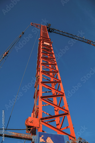 Close-up of crane in a construction area at sunset and blue sky in Tielt. Charming and quiet village in the countryside, near Ghent and surrounded by agricultural fields. Western Belgium. photo