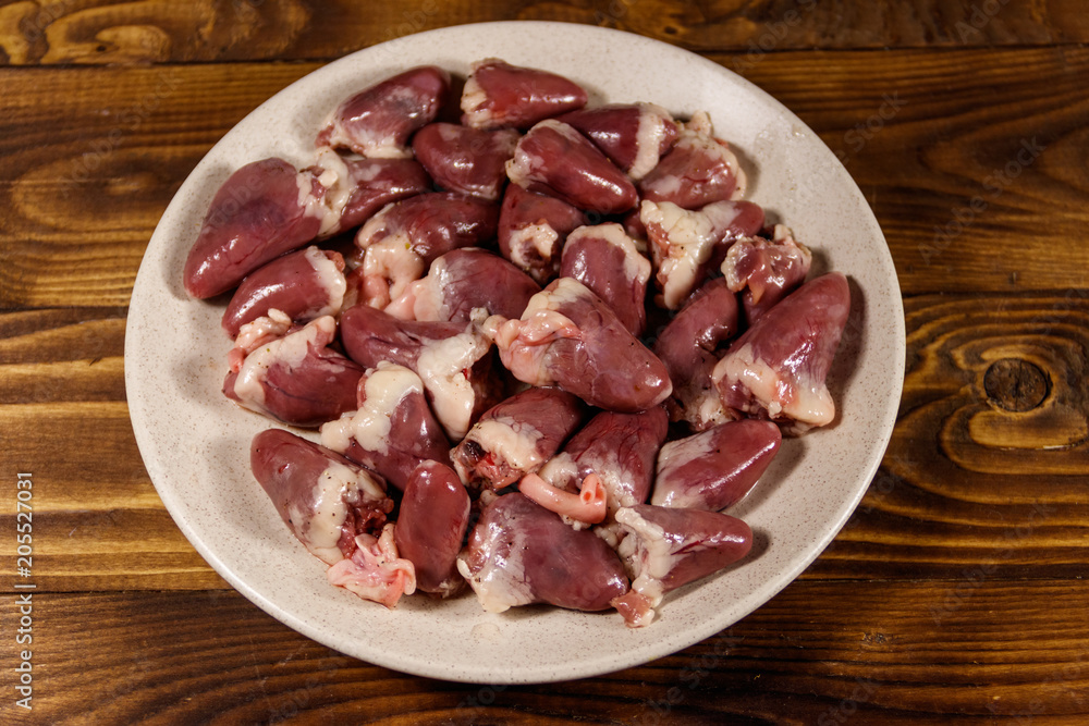 Raw chicken hearts on wooden table