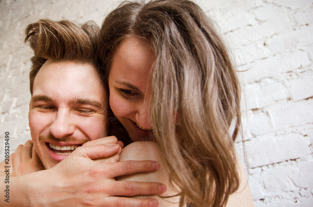 happy half-nude loving couple hugging against a brick wall background. close-up. happy half-nude loving couple hugging against a brick wall background. close-up.