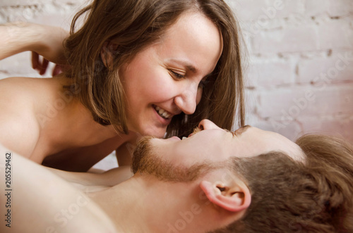 Photography happy half-naked loving couple lies on a bed on brick wall background