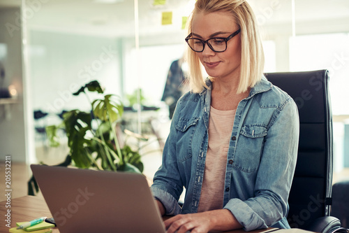 Confident young businesswoman using a laptop in her office