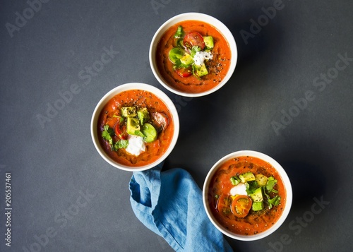 Chilled heirloom tomato gazpacho soup topped with avocado, cherry tomatoes, cilantro and a dallop of sour cream photo