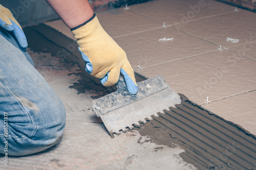 notched trowel in the hands of the tiler