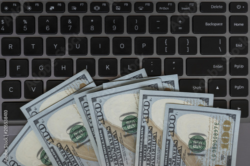 Dollars banknotes and black laptop keyboard as a background. American dollars money. Several hundred dollars bill