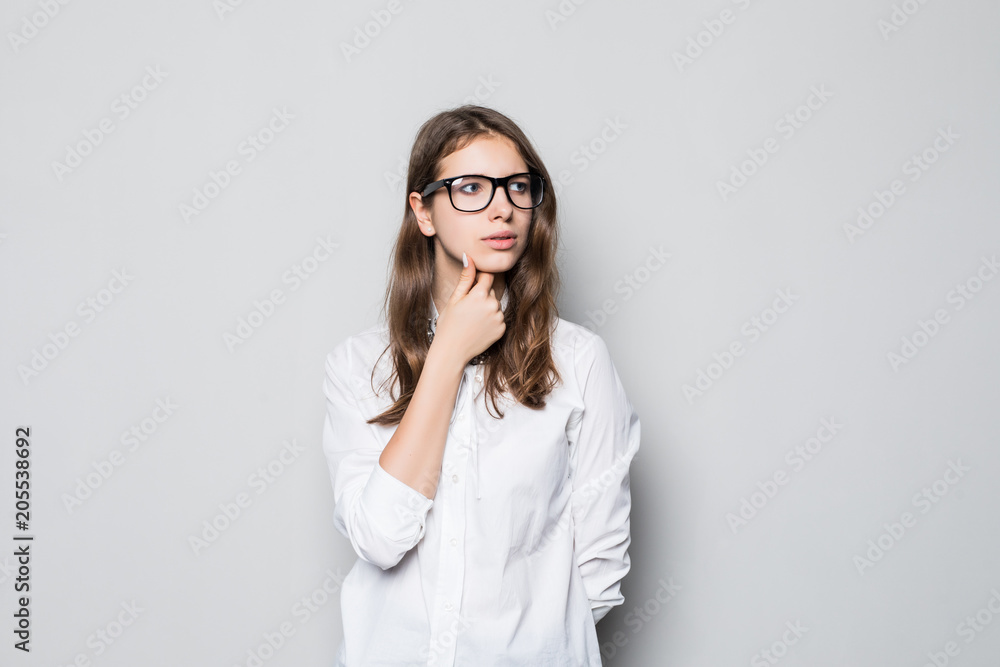 Pretty young office woman with finger on chin isolated on gray Pretty young office woman with finger on chin isolated on gray