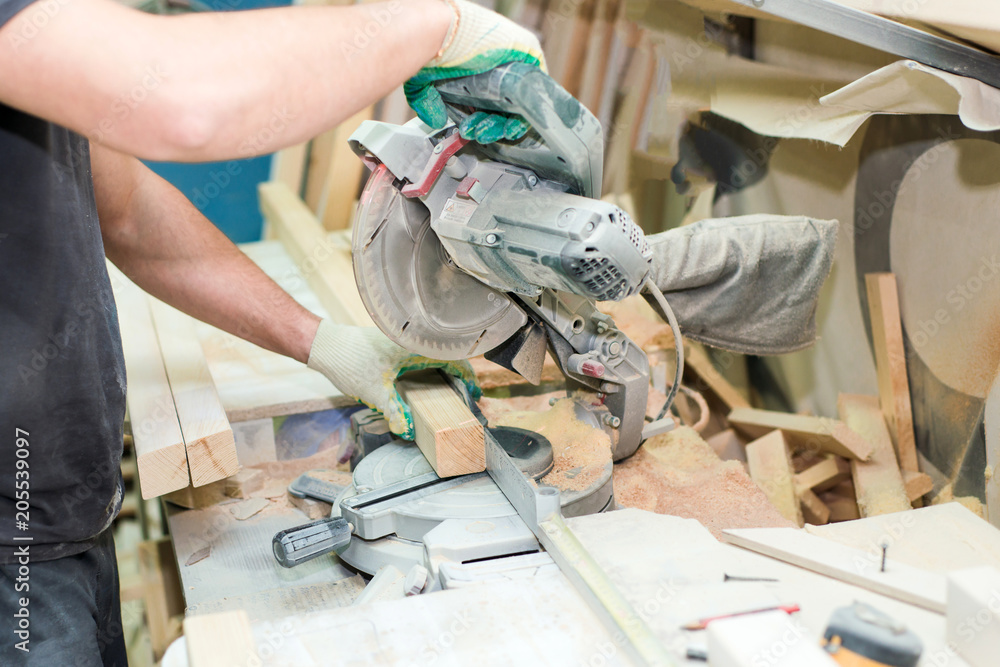 Wood processing. Man sawing wooden bars with electric saw Wood processing. Man sawing wooden bars with electric saw