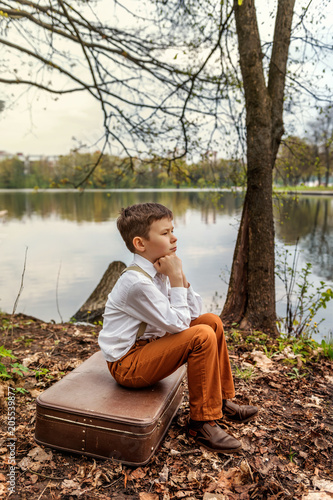 Fotografie a brooding rustic simpleton fellow sitting on a retro old-fashioned suitcase on