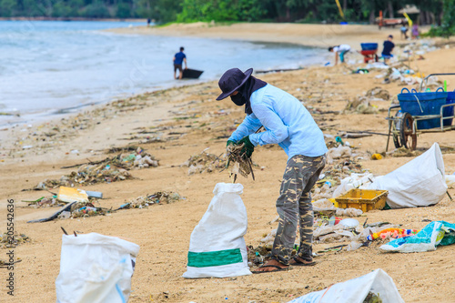 Men are collecting lots of trash blow from sea to the beach.