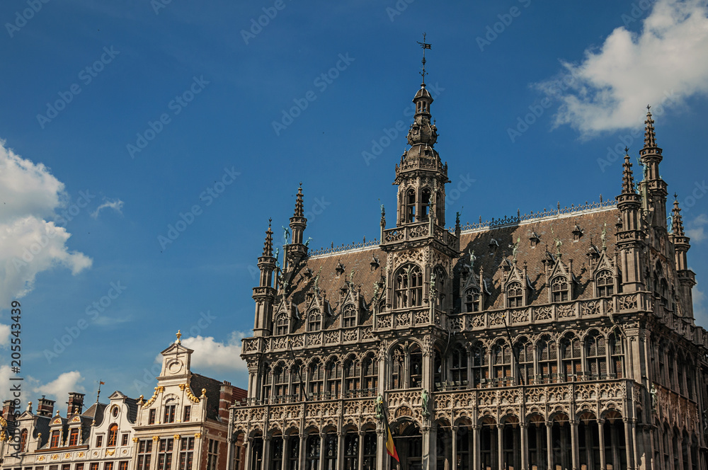 Richly decorated facade in Gothic style of Brussels City Museum and Belgian flag, at Grand Place. Vibrant and friendly, is the country’s capital and administrative center of the EU. Central Belgium