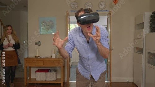 VR headset man caught cheating at home with virtual. static shot of millennial man wearing VR headset clearly doing something naughty, girlfriend finds him and gets upset, leaving