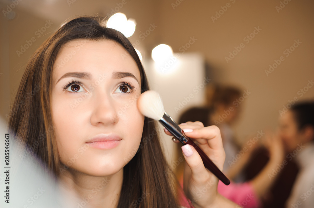 Fototapeta premium Make up artist doing professional make up of young woman. Beauty shcool.