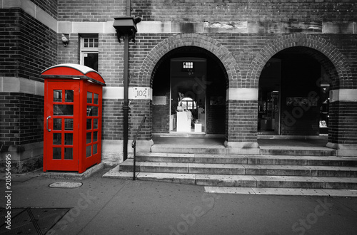 Black and white street scene with selective color on a red phone box in Sydney, Australia