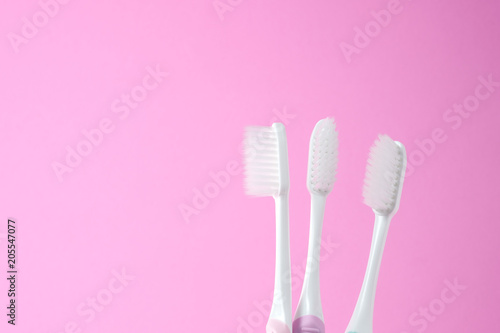 Close-up three white plastic toothbrush on pink background