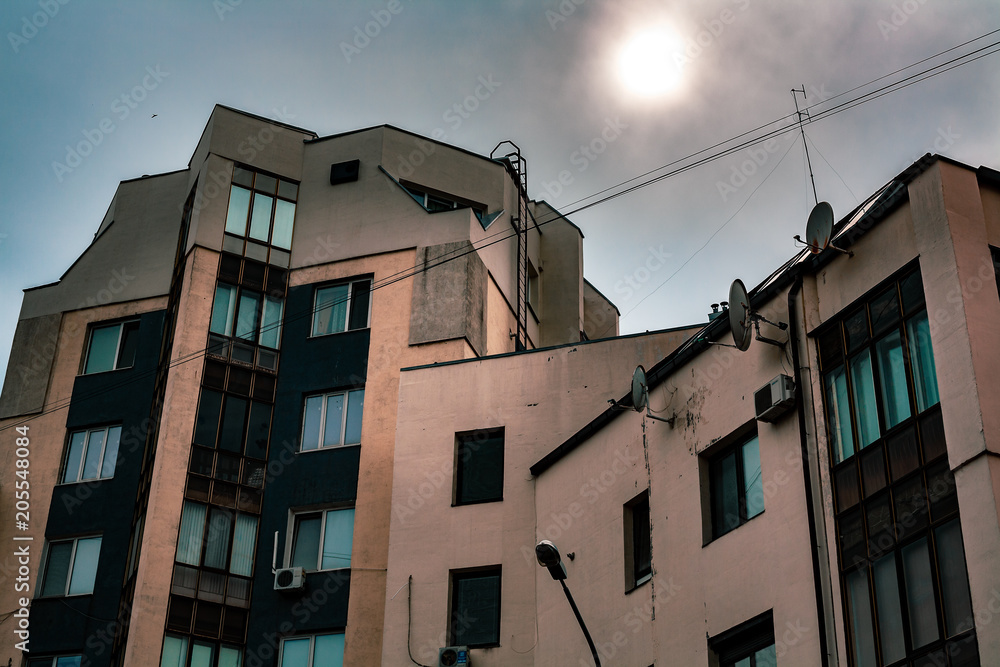 Building facade in gloomy weather with sun looking through the clouds Building facade in gloomy weather with sun looking through the clouds